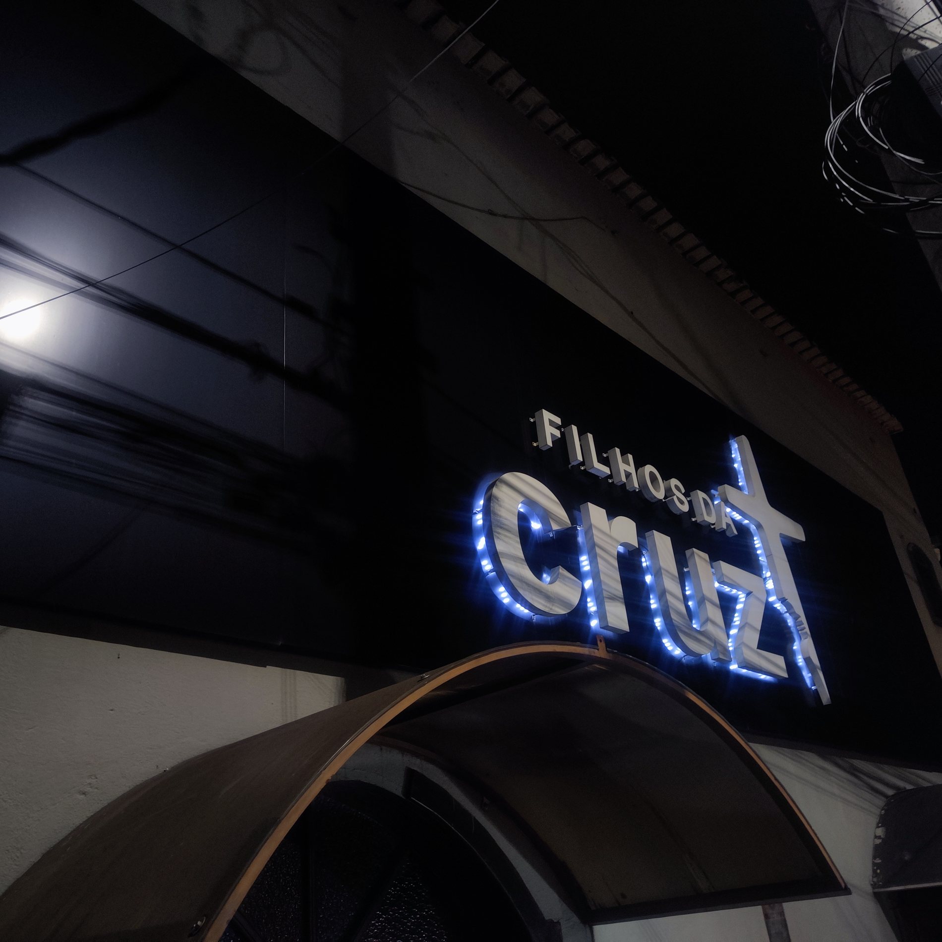 Letreiro Filhos da Cruz em fachada noturna