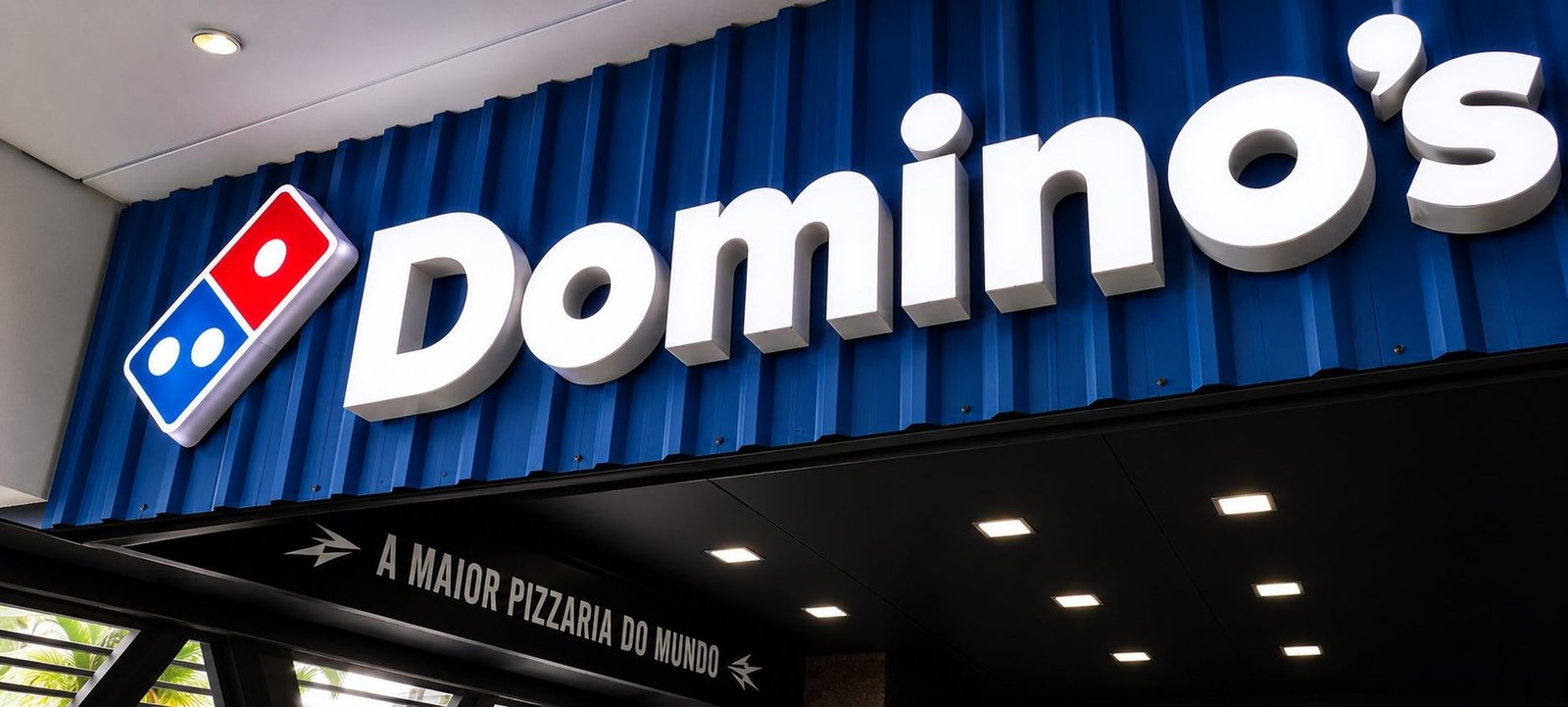 Letreiro luminoso Domino's em fachada azul
