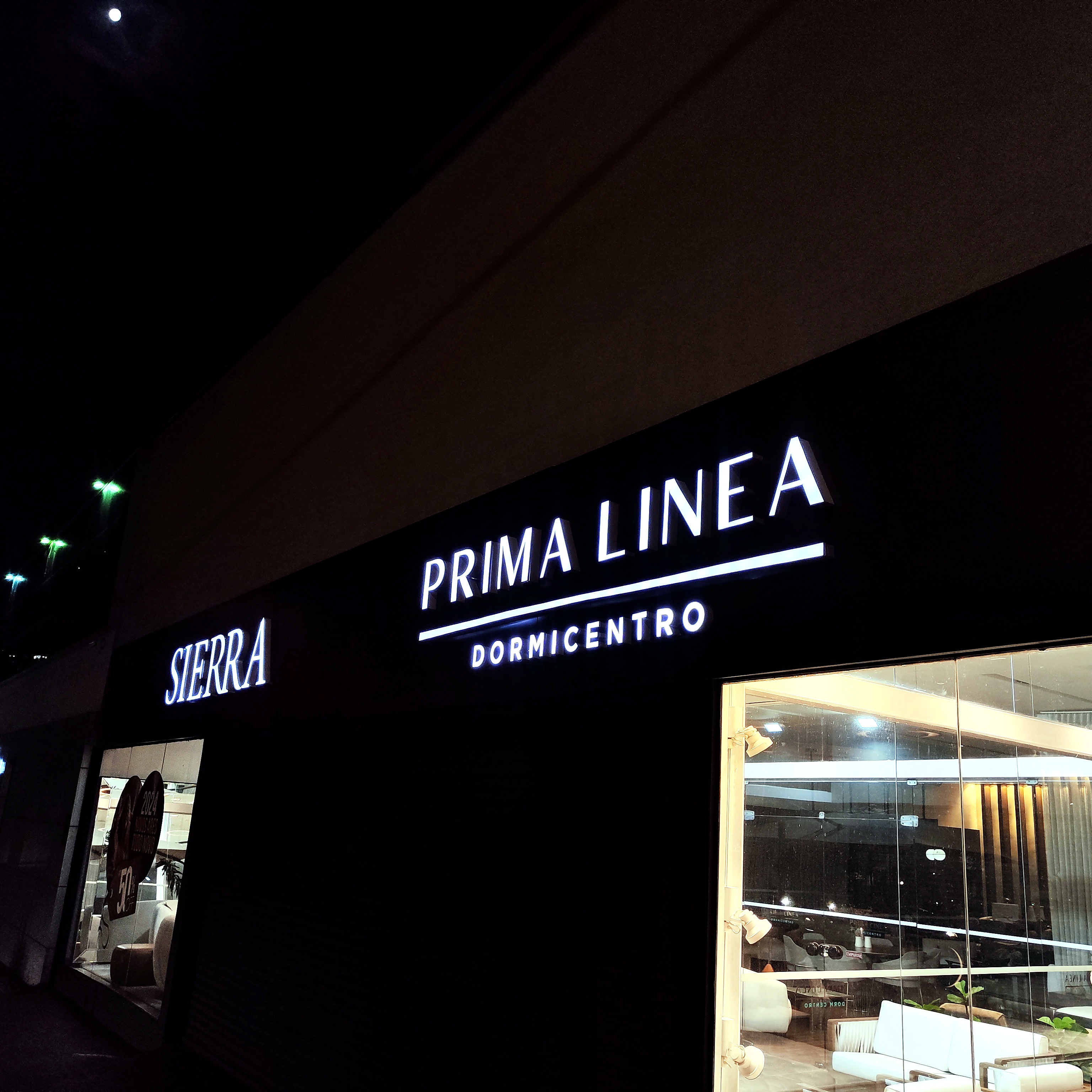 Letreiro luminoso Prima Linea em fachada comercial noturna